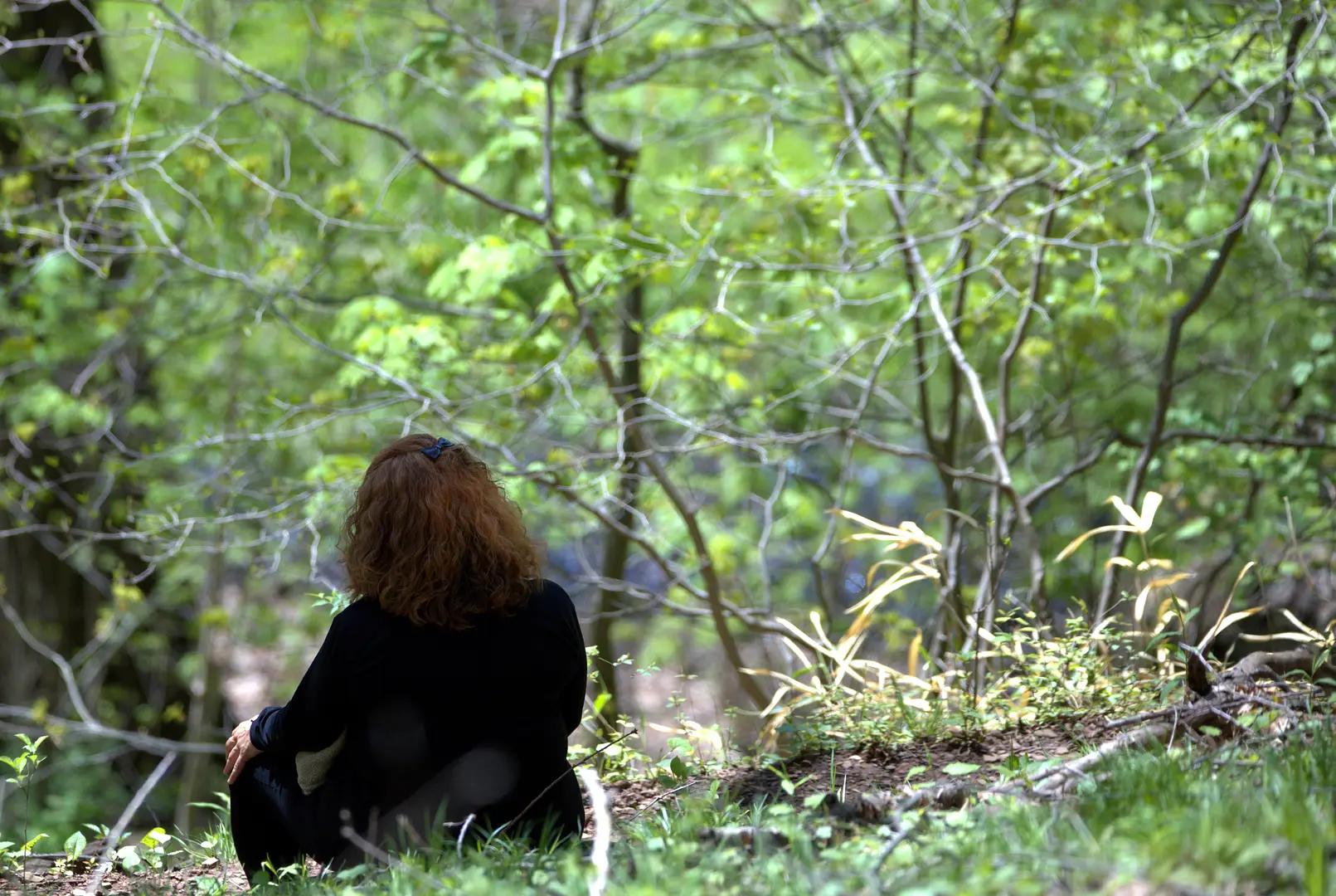 Une personne les yeux fermés, adossée à un arbre en forêt